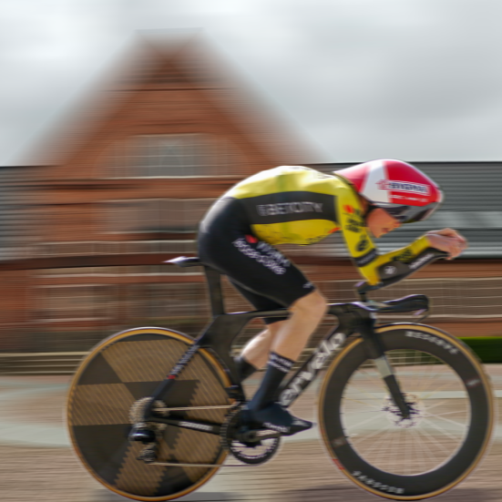 Jonas Vingegaard i gul førertrøje sprinter forbi Brønderslev Bibliotek, der ses sløret i baggrunden. Fotocollage. 
