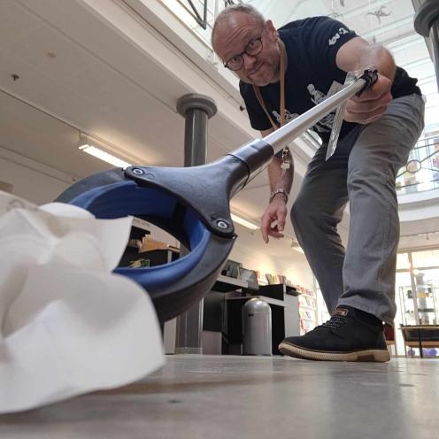 Bibliotekets formidler Hans samler affald på biblioteket med en affaldsiopsamler