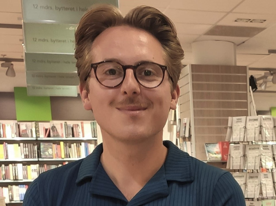 Forfatteren Thomas Korsgaard har en blå skjorte på og kigger ind i kameraet. 