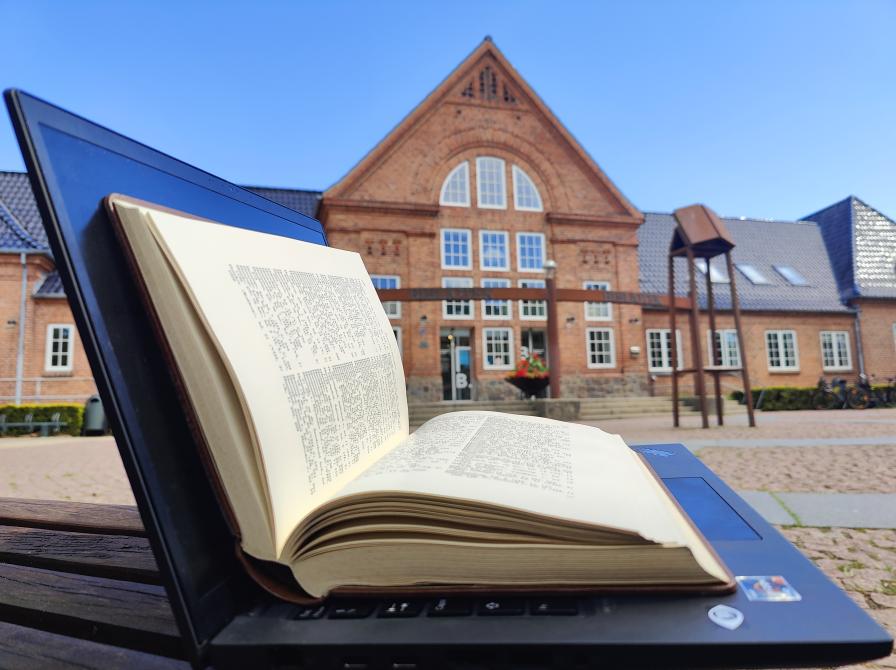 Opslået computer med opslået leksikon lagt ovenpå
