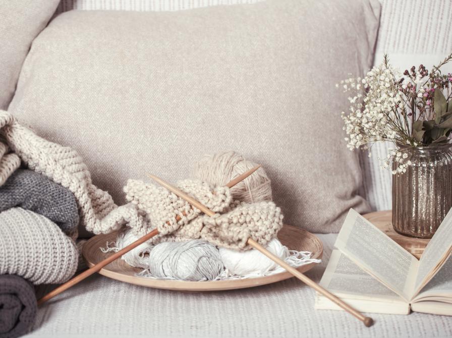 Strikketøj og opslået bog ligger i en sofa